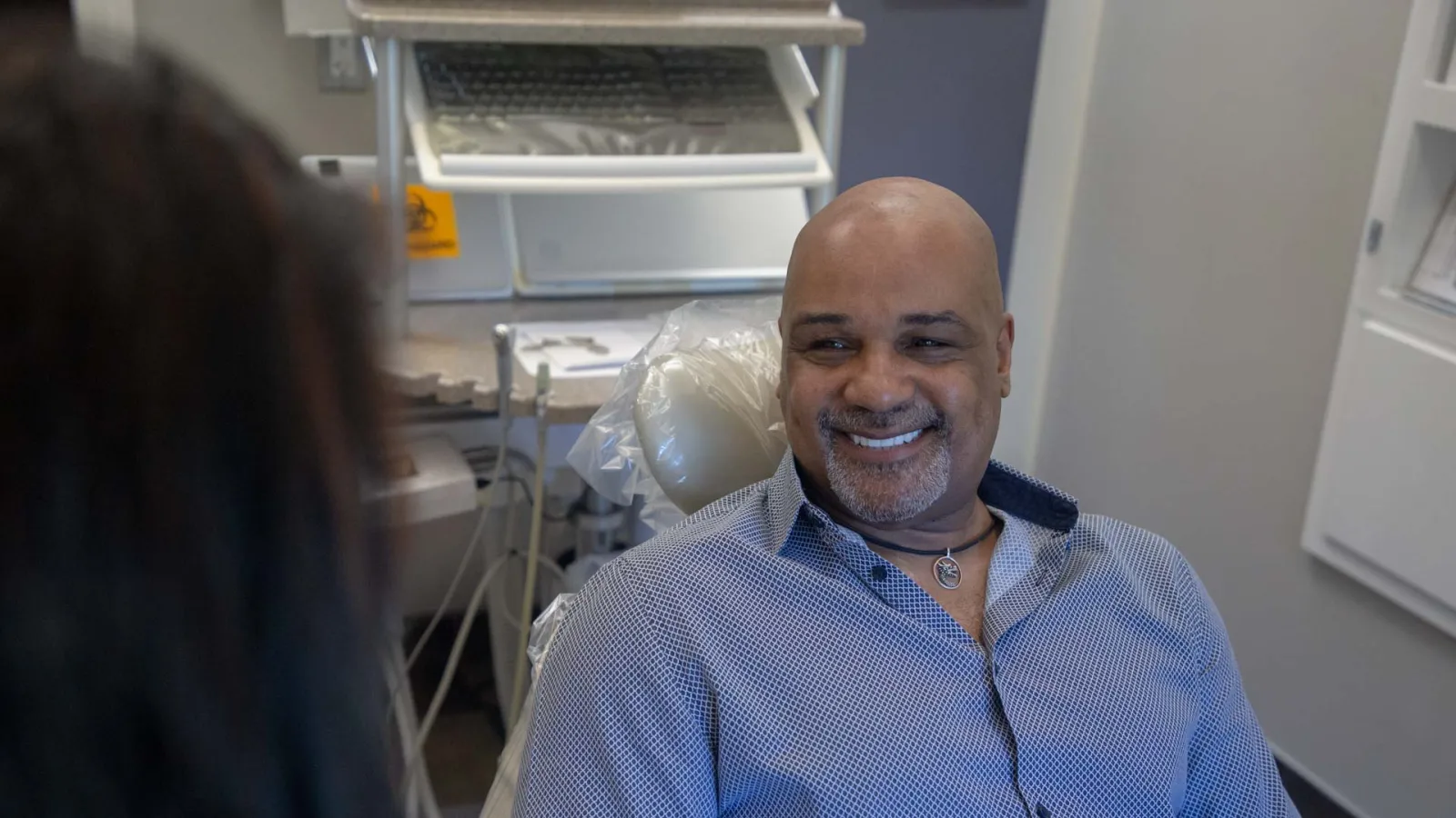 Smiling man sitting in a dental chair during a dental appointment in a modern clinic room.